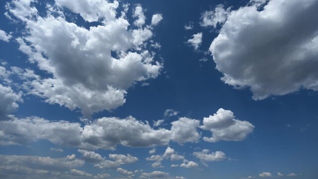 Timelapse of dramatic summer clouds building and evolving across a bright blue sky creating a powerful shifting cloudscape with dynamic natural motion