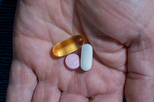 Three different pills and capsules in a human hand. Hand holding gel capsule and tablets. Concept of daily medication intake supplements vitamins or healthcare routine for wellness and recovery