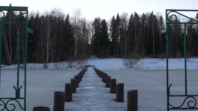 4K winter sunset timelapse over a frozen lake with an abandoned pier pile. Calm, windless atmosphere with minimal movement, distant trees and a smooth transition from white sky to dark evening tones.
