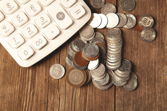 Coins and calculator on wooden table, closeup. Financial concept