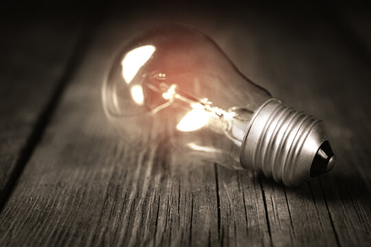 Glowing light bulb on wooden background, concept of idea and innovation