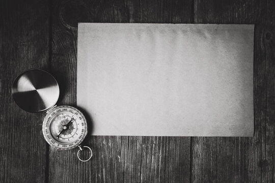 Compass and blank paper on wooden background. Vintage style toned picture