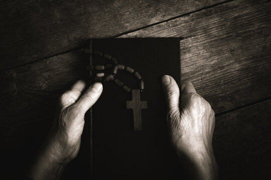 Man hands holding a rosary on the holy bible. Religion concept.