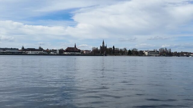 Konstanz, Germany &ndash; April 2026: POV from pedal boat on Lake Constance with calm water, shoreline, natural landscape and people in background, public outdoor leisure and travel scene