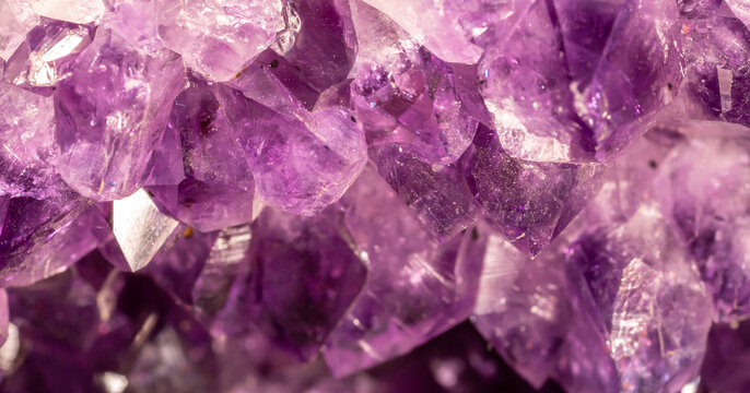 Amethyst purple crystals. Gems. Mineral crystals in the natural environment. Texture of precious and semiprecious stones. Seamless background with copy space colored shiny surface of precious stones.