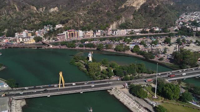 Drone view of haridwar showing traffic on highway bridge with shiva statue and holy ganga river