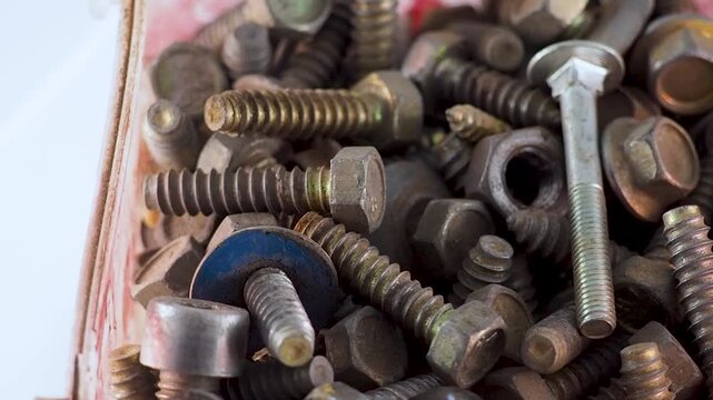 Old rusty metal screws and bolts in a container