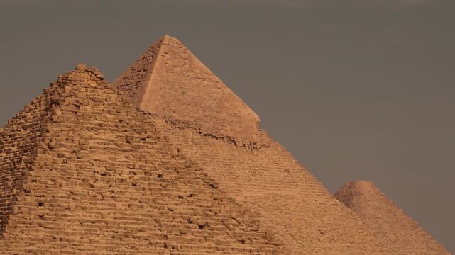 Pan capturing the tops of all three Giza pyramids. A cinematic shot of the Giza pyramids, showing the tops of all three pyramids in a single frame