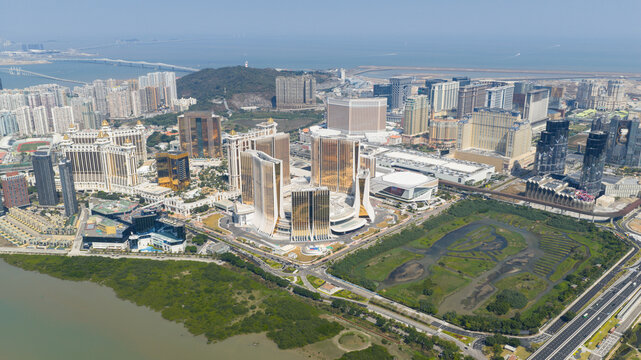 Macao - 18 February 2026: Aerial view of Grand Lisboa Palace Resort Macau and the Cotai Strip skyline with modern skyscrapers, lush green wetlands, and the sea under a clear blue sky.