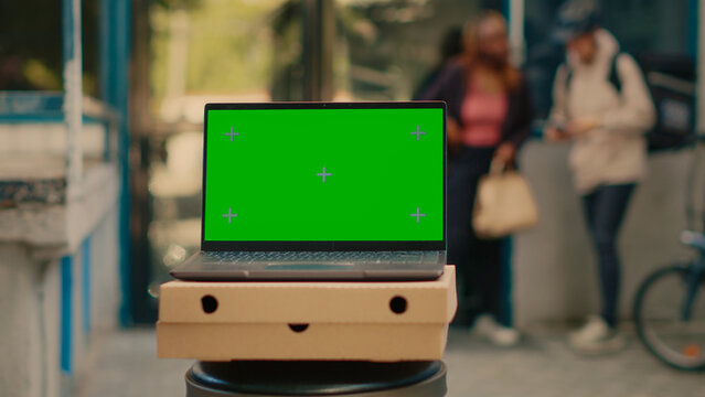 Laptop advertising greenscreen template outside, food delivery service at front door. Running isolated chroma key display with blank mockup and copyspace background on computer screen.