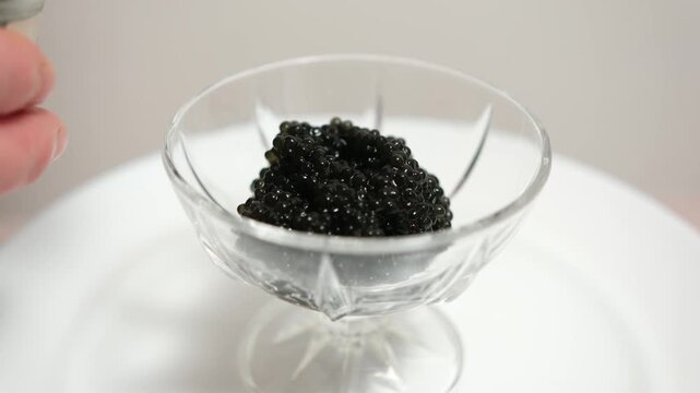 Omega-3, healthy fats, luxury seafood indulgence black caviar served with teaspoon from glass dish. Gourmet treat, nutrition-rich, elegant home presentation.