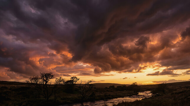 Dramatic sunset sky with dark storm clouds over a river valley landscape at dusk