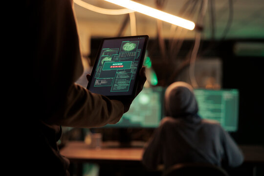 Thief reading access denied message on tablet, hacker failing to crack firewall encrytion and steal data. Internet criminal using malicious software, to break and crack passwords.