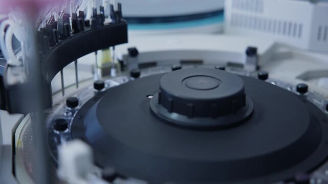 Slow motion rotation of laboratory analyzer carousel with reagent tubes in clinical diagnostics lab.