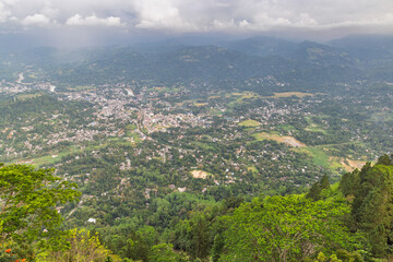 Obraz premium View from Ambuluwawa Tower, multi-religious temple complex located in Gampola, in Sri Lanka. Panoramic Aerial View of a Vibrant Town Nestled Amidst Lush Green Hills and Clouds