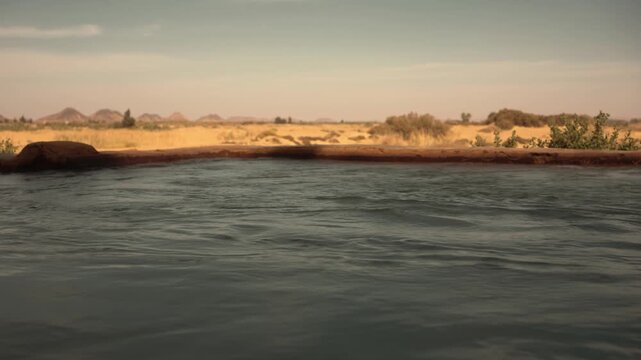 Desert oasis irrigation system, Egypt. A mini-story from an Egyptian desert oasis showing water infrastructure for agriculture: a pump, a flowing pipe, and a small irrigation pool.
