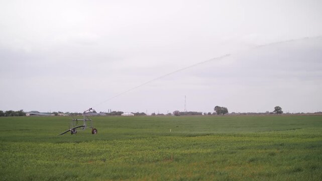 High-angle long shot of an industrial center pivot irrigation system operating across a vast green agricultural field