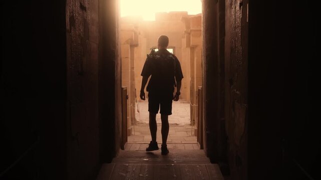 Silhouette Exiting Main Chamber &ndash; Hatshepsut Temple. Cinematic symmetrical shot of a tourist in silhouette walking toward the exit of the main chamber at Hatshepsut Temple in Luxor.
