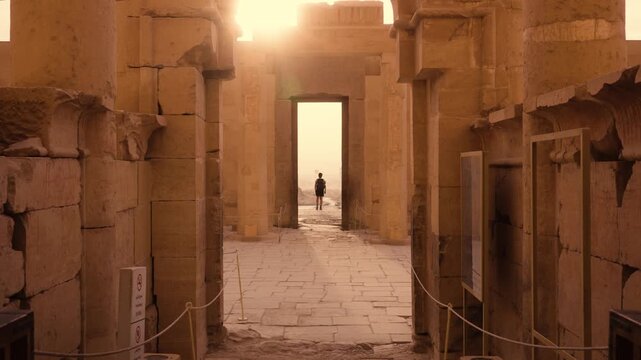 Symmetrical Shot &ndash; Hatshepsut Temple Exit. Cinematic symmetrical shot at Hatshepsut Temple in Luxor, showing a tourist in silhouette framed by the tall rectangular doorway. 