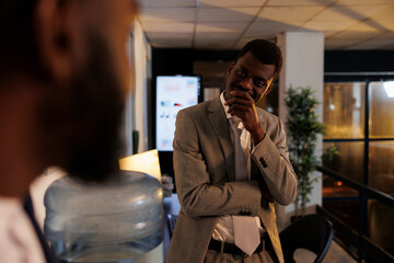 Fototapeta premium Relaxed businessman discussing company profit with manager during work break in startup office. Employees working late at night, planning investment strategy plan. Business concept