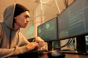 Male hacker trying to break into government network, coding computer virus on database late at night. Young spy planning data breach to hack computer system, stealing sensitive information. © DC Studio