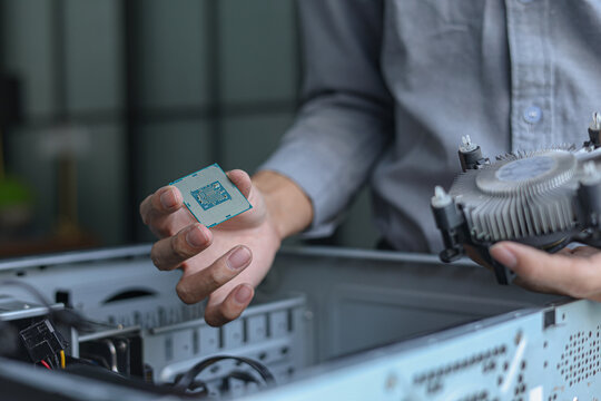 Computer engineer repair and assembling high-performance PC, CPU and cooler at workshop desk.