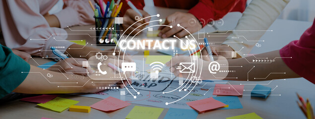 Obraz premium A diverse group works together at a table covered with colorful sticky notes and digital icons to symbolize modern communication and collaboration methods. Trope