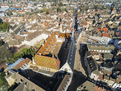 Beaune, France - 05 April 2026: Aerial view of Hotel-Dieu Museum - Hospices de Beaune with its iconic colorful glazed tile roof and historic courtyard in the heart of the town.