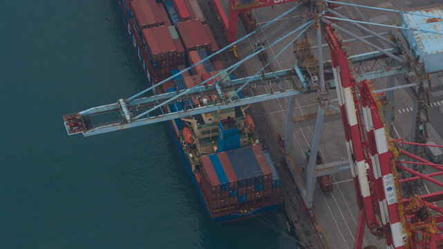 Keelung City, Taiwan - 20 February 2026: Aerial view of the Inner Harbor of Keelung with a large container ship docked at the pier and red and white gantry cranes loading cargo.