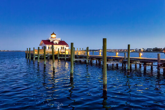 A nice seascape at the golden hour before sunset of the Roanoke Marshes cottage Lighthouse in Manteo, North Carolina with lights reflecting in the ocean water.