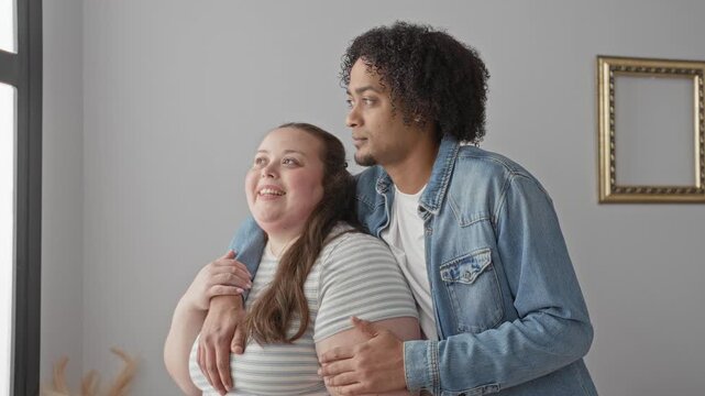Man holding plus size woman with arm around shoulder and hand on upper arm, both smiling in studio; intimacy love connection.