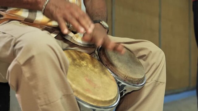Plano cerrado de Manos tocando bongos doble de cuero y madera