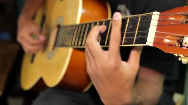 Plano cerrado de manos tocando guitarra cl&aacute;sica