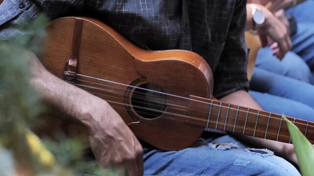 Manos de hombre tocando instrumento cuatro venezolano
