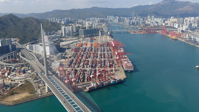 Hong Kong - 15 February 2026: Aerial view of Hong Kong International Terminals with red gantry cranes, stacked containers, and the Stonecutters Bridge spanning the water.
