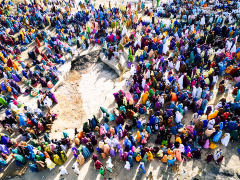Zaria, Nigeria - 28 October 2025: Aerial view of a large crowd of people gathered for prayer at the Jum'at Mosque, Hayin Dogo Palladan, on a rocky landscape under bright sunlight.