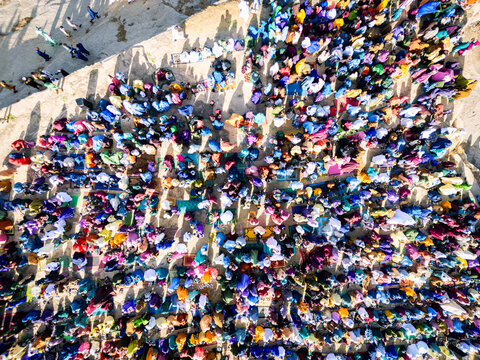 Zaria, Nigeria - 28 October 2025: Aerial view of a large crowd of people gathered for prayer at the Jum'at Mosque, Hayin Dogo Palladan, on a rocky landscape under bright sunlight.