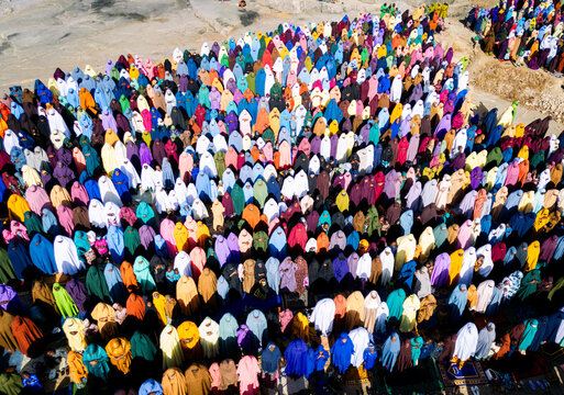 Zaria, Nigeria - 28 October 2025: Aerial view of a large crowd of people gathered for prayer at the Jum'at Mosque, Hayin Dogo Palladan, on a rocky landscape under bright sunlight.