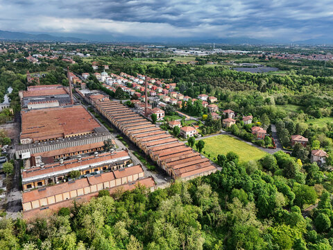 Aerial view of the Industrial Village of Crespi d'Adda featuring historic factory buildings and chimneys surrounded by lush greenery in Capriate San Gervasio, Lombardia, Italy.