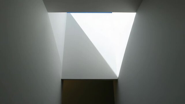 Minimalist interior skylight casting geometric light and shadow across smooth white walls and soft