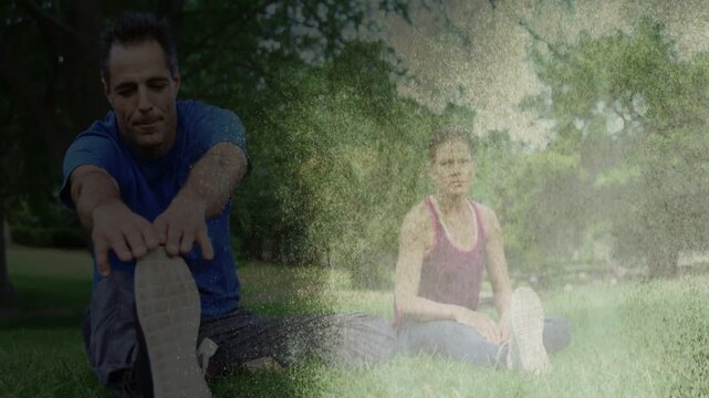 Man and woman doing hamstring stretch in park, fading light streak revealing posture for fitness