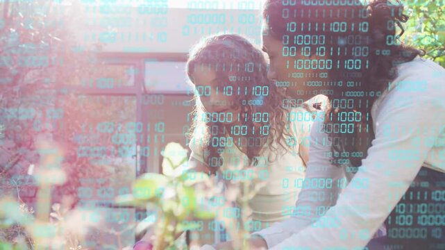 Woman leaning guiding girl's hands while girl gardening turquoise binary digits floating over hands