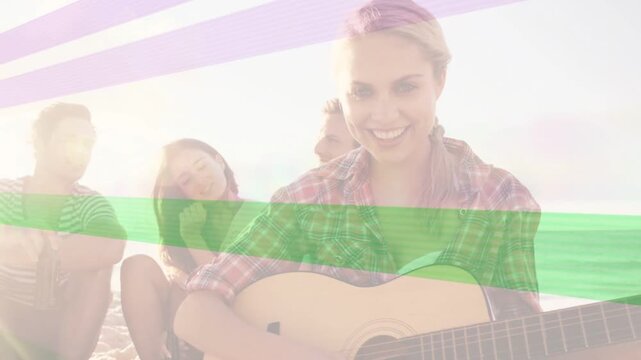 Guitarist tuning guitar then strumming, singing music for friends on beach, bands crossing frame