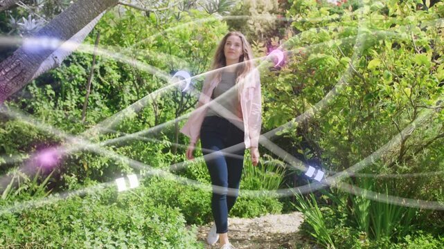 On cue woman walking garden path toward camera, ribbons and orbs sweeping over her for fashion