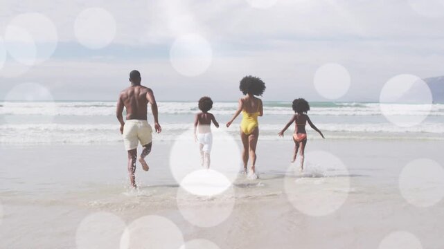 Family running toward waves on spotting surf, splashing for family fun travel with bokeh overlay