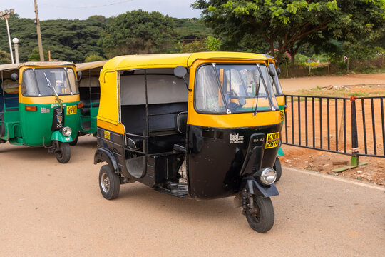 Two Bajaj RE auto rickshaws parked on a roadside in India