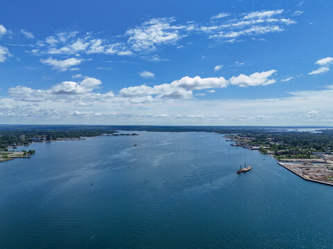 Aerial view of the Saint Marys River with a small barge on the blue water under a bright sky with scattered clouds in Sault Ste. Marie, Ontario, Canada.