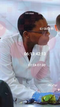 Vertical video: Lab tech inspecting pipette, responding to colleague, timecode overlay, glasses