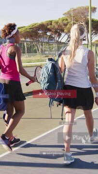 Vertical video: After practice two women walking across tennis court with rackets while UI tracking