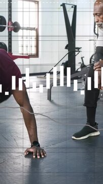 Vertical video: Coach cueing man doing plank climbers in gym, graphics syncing with watch for form
